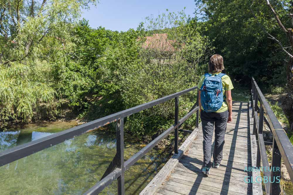 Wanderin geht über eine Brücke, die den Fluss Krupa in Krupa na Vrbasu überspannt.
