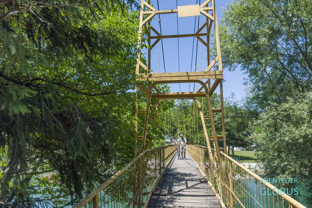 Radfahrer auf gelber Hängebrücke über den Fluss Vrbas bei Krupa na Vrbasu