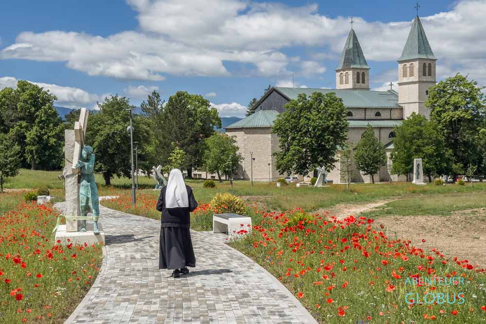 Nonne auf Kreuzweg mit Skulpturen und die Kirche St. Peter und Paul im Franziskanerkloster in Livno
