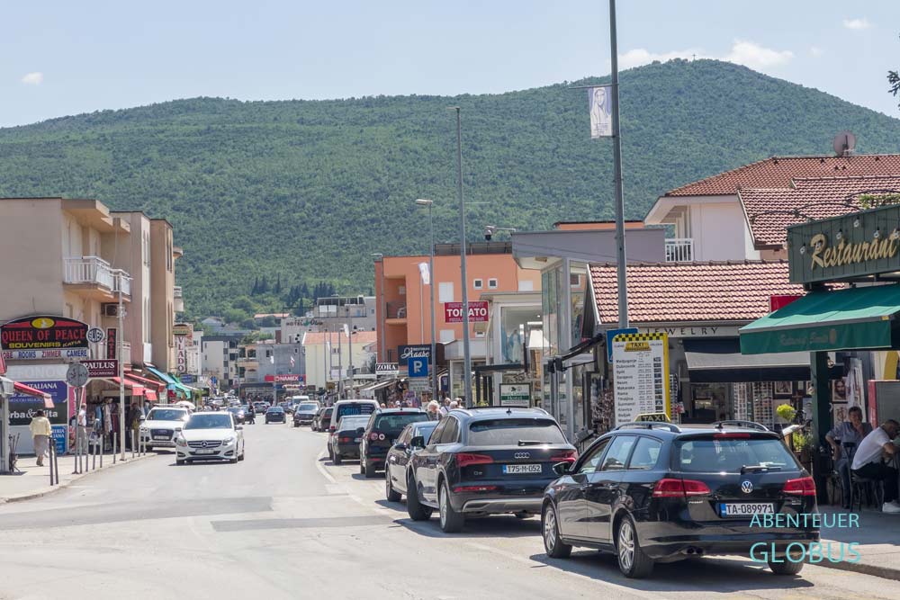 Medugojre, Straßenszene mit Häusern und Autos und Kreuzberg im Hintergrund