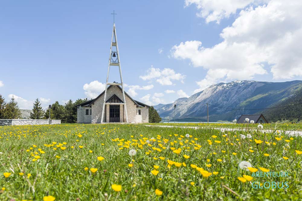 Blumenwiese und Kirche Unserer Lieben Frau vom Schnee (Crkva Gospe Snjezne) am Restaurant Jelinak im Dorf Barzonja am Blidinje-See im Naturpark Blidinje
