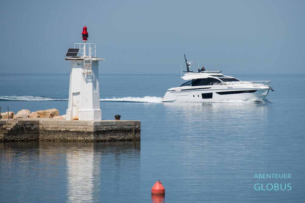 Mole (Novigradski mol) mit kleinem, weißen Leuchtturm, dahinter ein Motorboot in Novigrad
