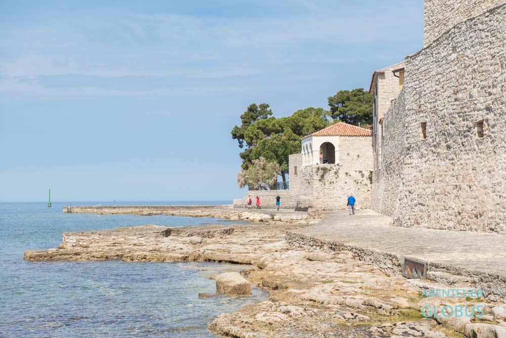 Spaziergänger auf der Promenade unterhalb der Stadtmauer mit der Loggia Belvedere in Novigrad, Istrien