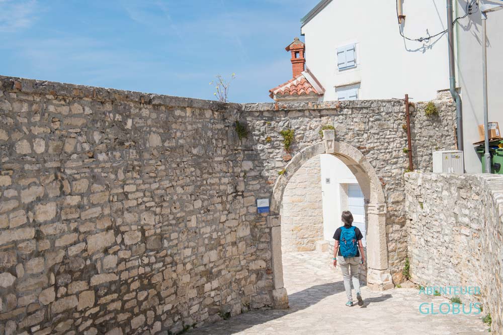 Touristin am Porta a Marina (Hafen- bzw. Meerestor) Teil der Stadtmauer in Novigrad, Kroatien