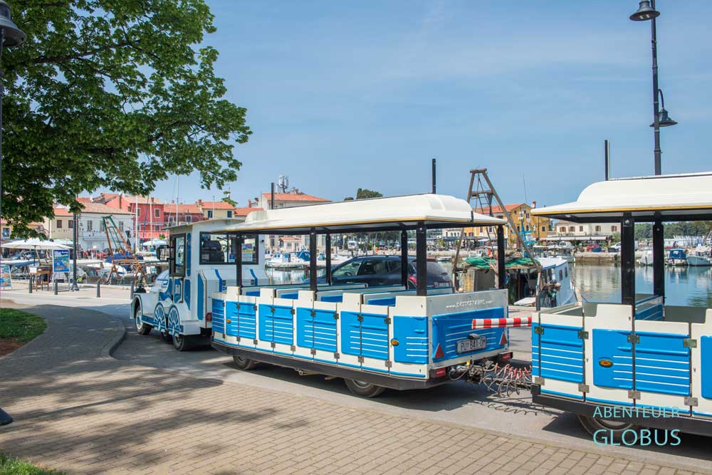 Blau-weiße Touristenbahn am Stadthafen Mandrac in Novigrad