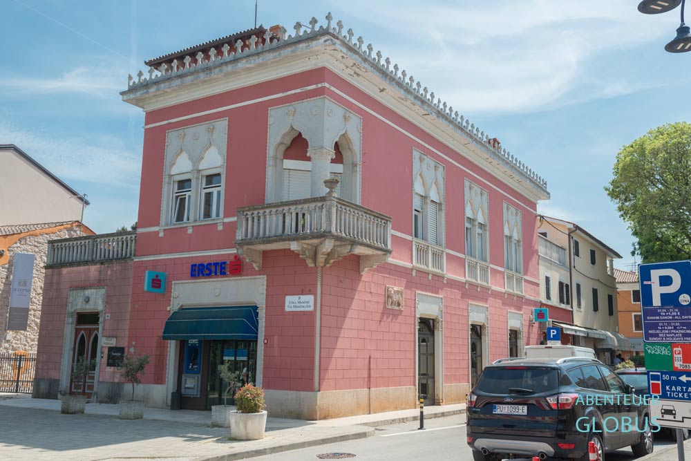 Rosafarbene Villa Venezia mit spätgotischen Zwillingsfenstern und parkende Autos daneben in Novigrad auf der Halbinsel Istrien