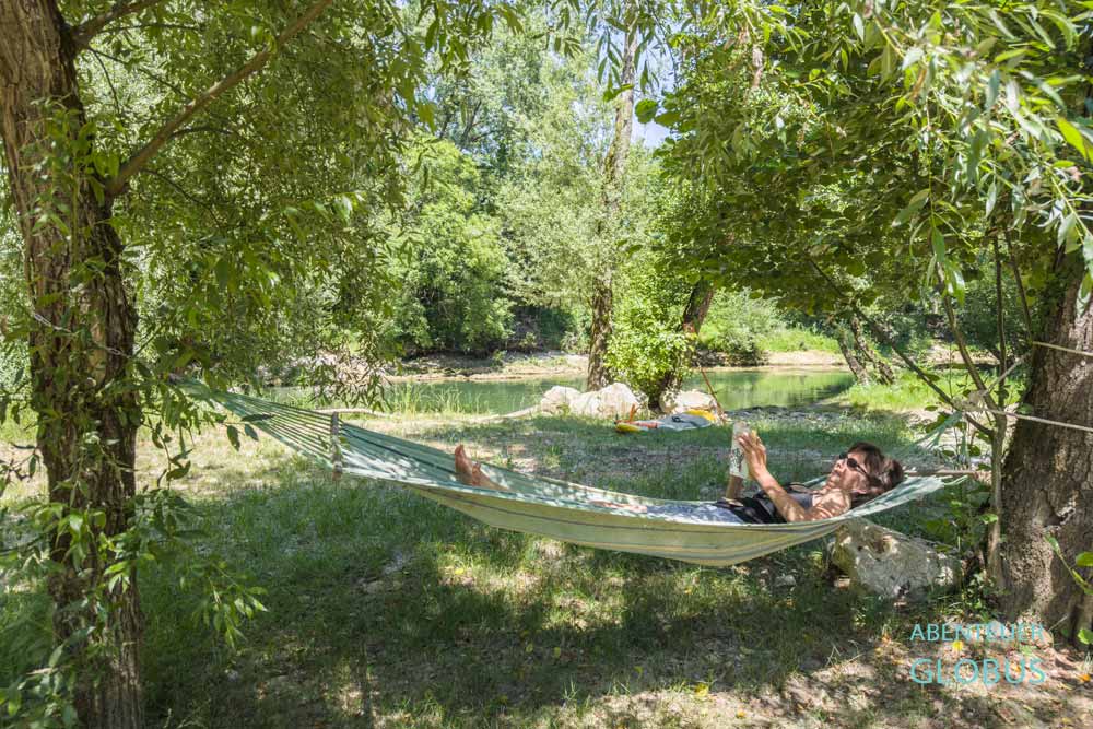 Urlauberin in einer Hängematte, dahinter der Fluss Sana, auf dem Campingplatz Autocamp SAN Soul and Nature nahe Sanski Most