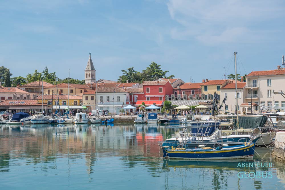 Boote im Stadthafen Mandrac von Novigrad, pastellfarbene Häuser und Glockenturm der Pfarrkirche St. Pelagius 