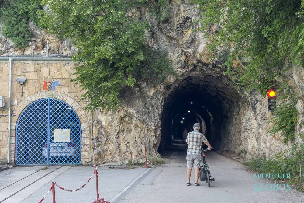 Radfahrer am Eingang des einstigen Eisenbahntunnels auf der Seite am Großen Pliva-See in Jajce