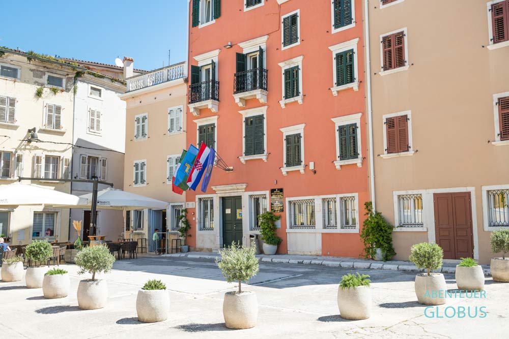 Rosafarbenes Rathaus und beige Häuser in der Altstadt von Vrsar in Kroatien