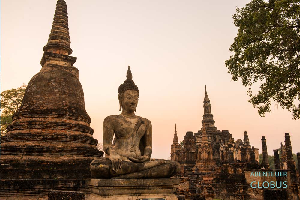Buddha-Statue und Tempel vor abendlichen Himmel in Alt-Sukhothai in Thailand