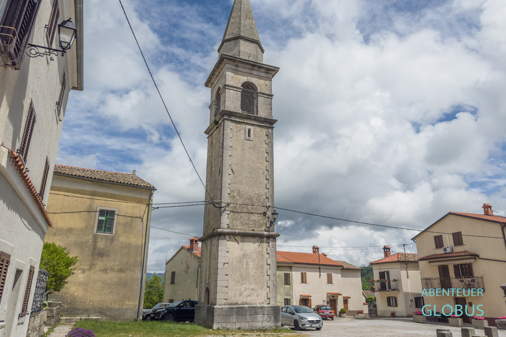 Heilig-Kreuz-Kirche mit Glockenturm auf dem zentral gelegenen Dorfplatz von Draguc in Kroatien