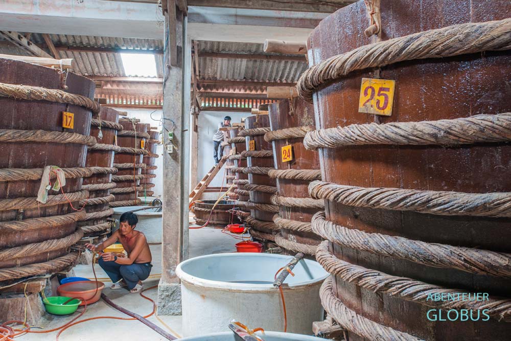 Ein Mann prüft die Qualität der Fischsoße in großen Fässern auf Phu Quoc in Vietnam.