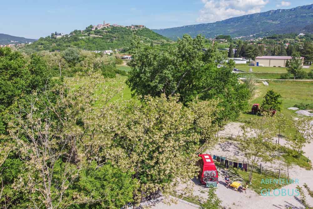 Roter Bulli VW T3 auf einem Stellplatz vom Campingplatz La Vita Camping, Stadt Buzet auf einem Hügel im Hintergrund, in Kroatien