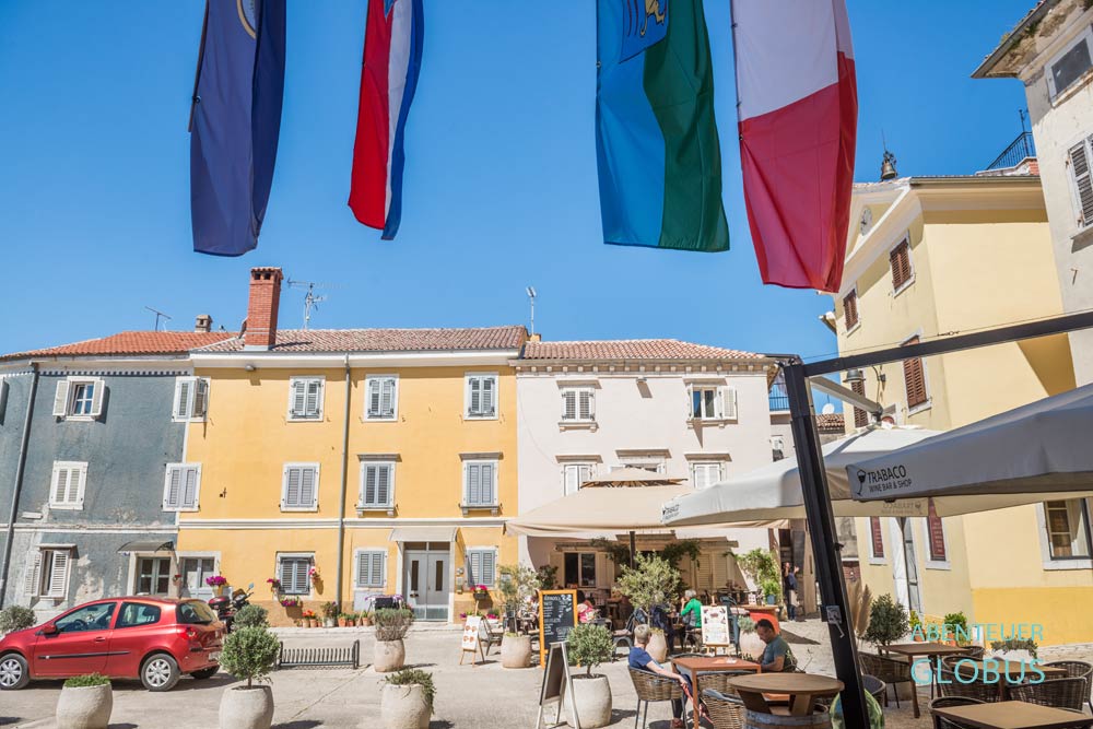 Pastellfarbene Häuser und Restaurants am Hauptplatz Degrassi in der Altstadt von Vrsar in Kroatien