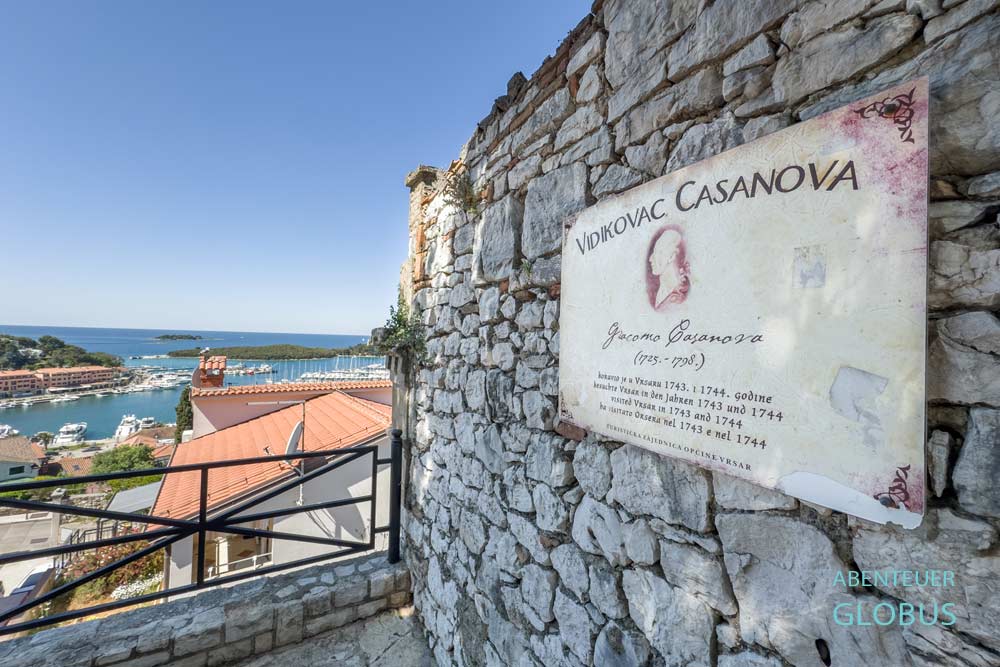 Schild auf Steinmauer am Aussichtspunkt Casanova mit Blick über Dächer zum Hafen von Vrsar in Kroatien