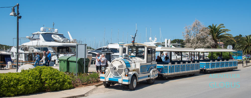 Blau-weiße Bimmelbahn an der Haltestelle am Hafen in Vrsar