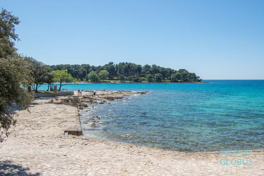 Strand Koversada mit gepflasterten Liegeflächen und Blick zur Insel Koversada