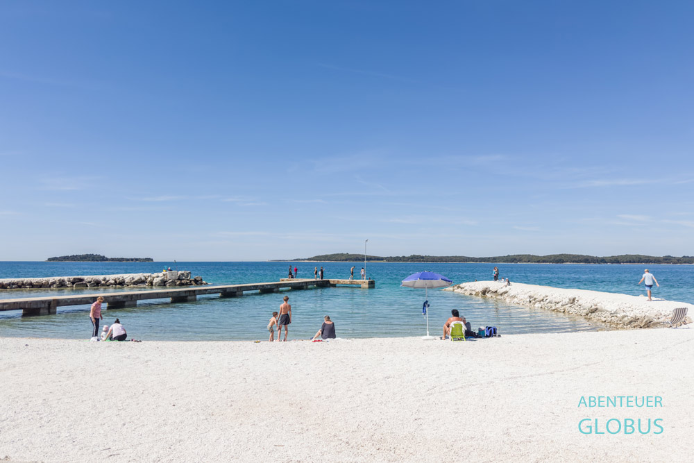 Bi Village Beach mit Badegästen und Stegen an der Adria in Fažana