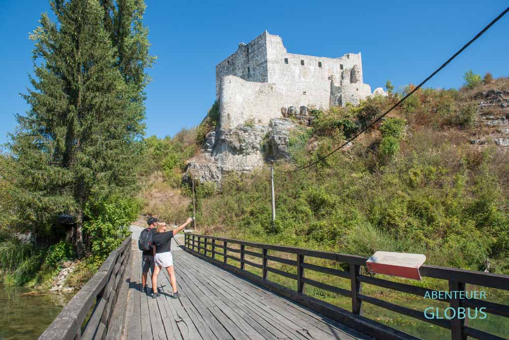 Zwei Touristen auf der Mocanov-Brücke, dahinter Stari Grad Slunj, die ehemalige Festung Slunj in Kroatien