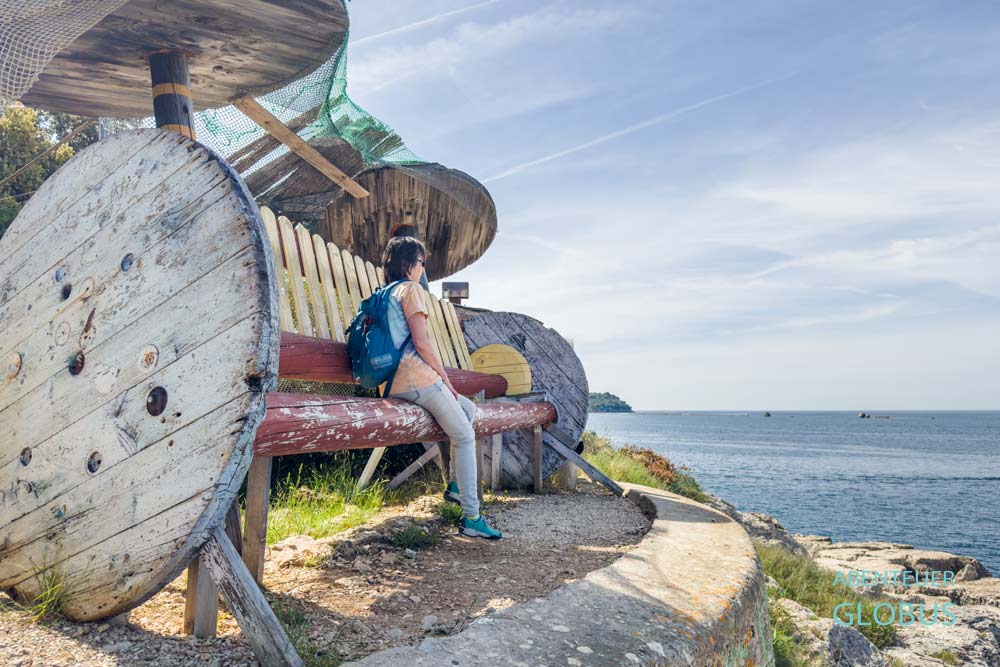 Frau auf einer Holzbank mit Blick auf die Adria am Strand Prostina in Istrien