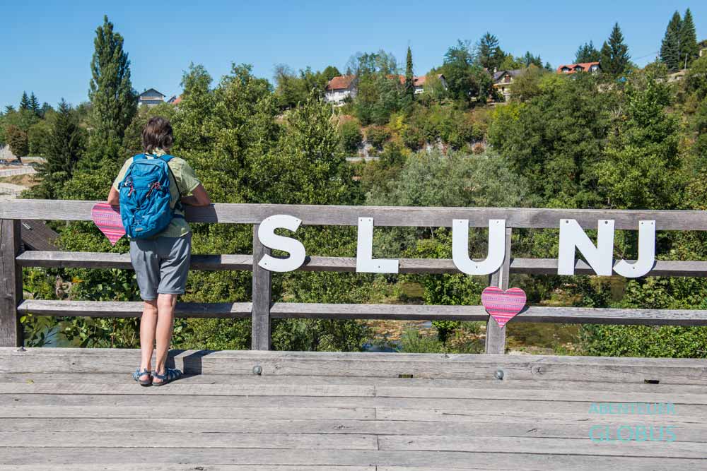 Besucherin auf der St.-Ivan-Nepomuk-Brücke mit dem Schriftzug Slunj