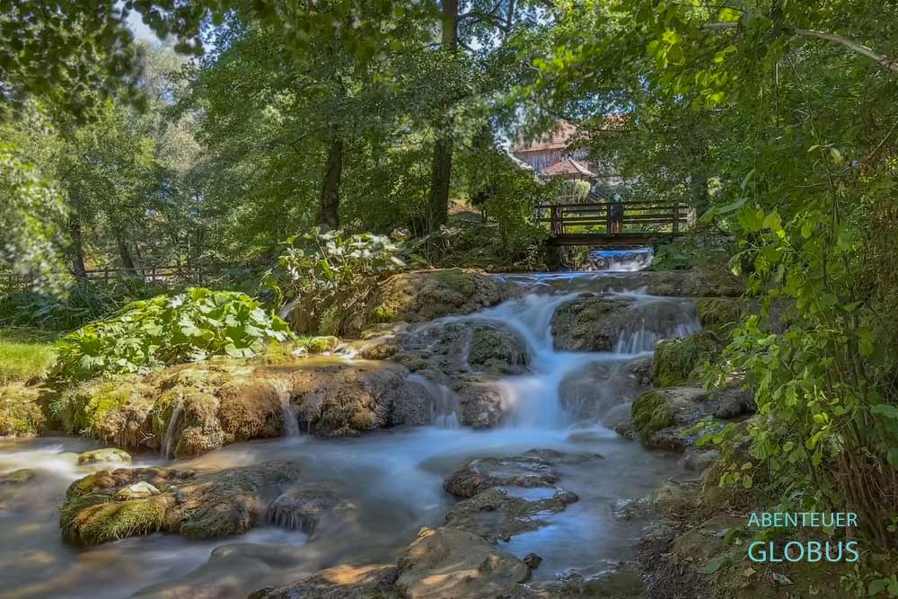 Kaskaden des Flusses Slunjcica, Holzbrücke mit Touristen im Hintergrund, in Rastoke, Slunj in Kroatien