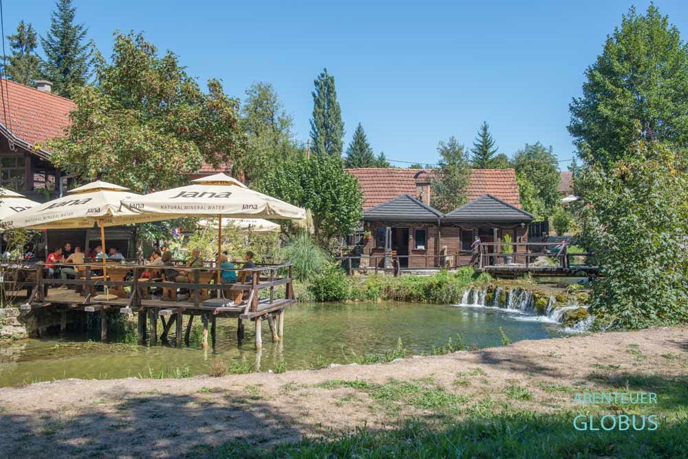 Restaurant mit Gästen auf der Terrasse und Wasserfall in Rastoke-Slunj